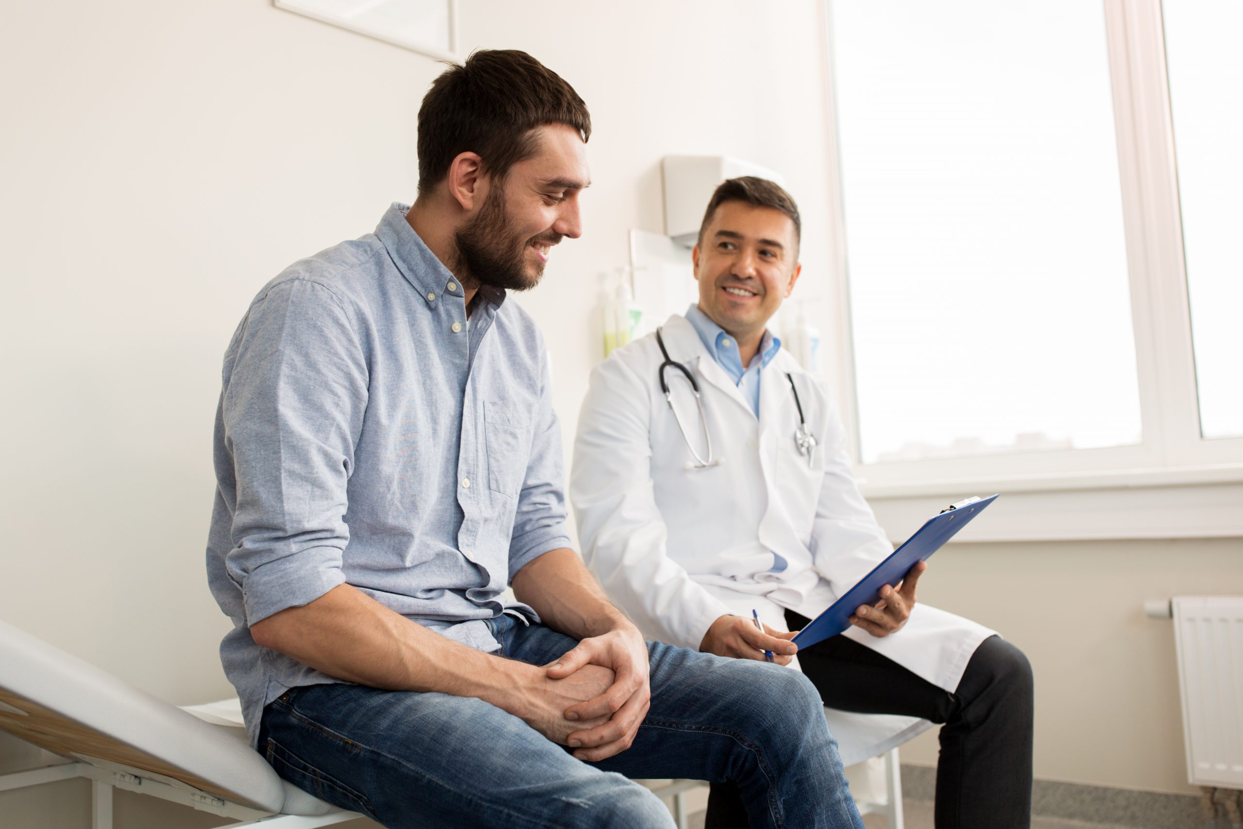 A young man meeting a doctor in an examination room for a wellness checkup, one of the important preventive services.