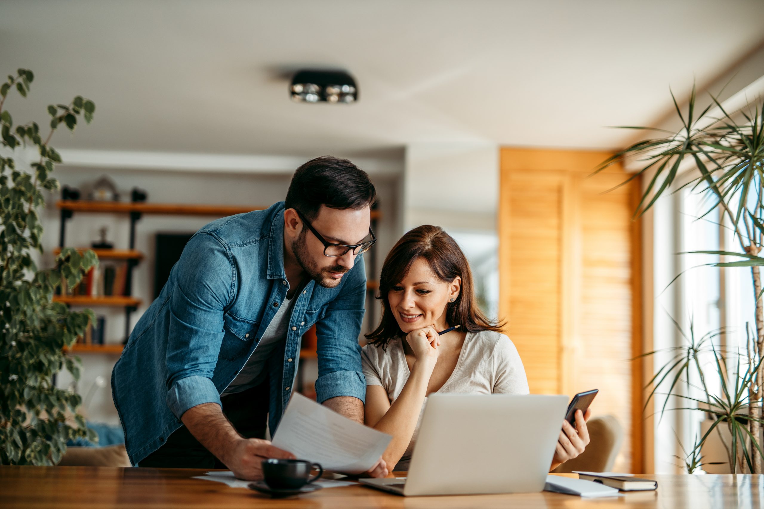 A couple at home with their laptop computer, considering health insurance options that include Silver-tier plans.