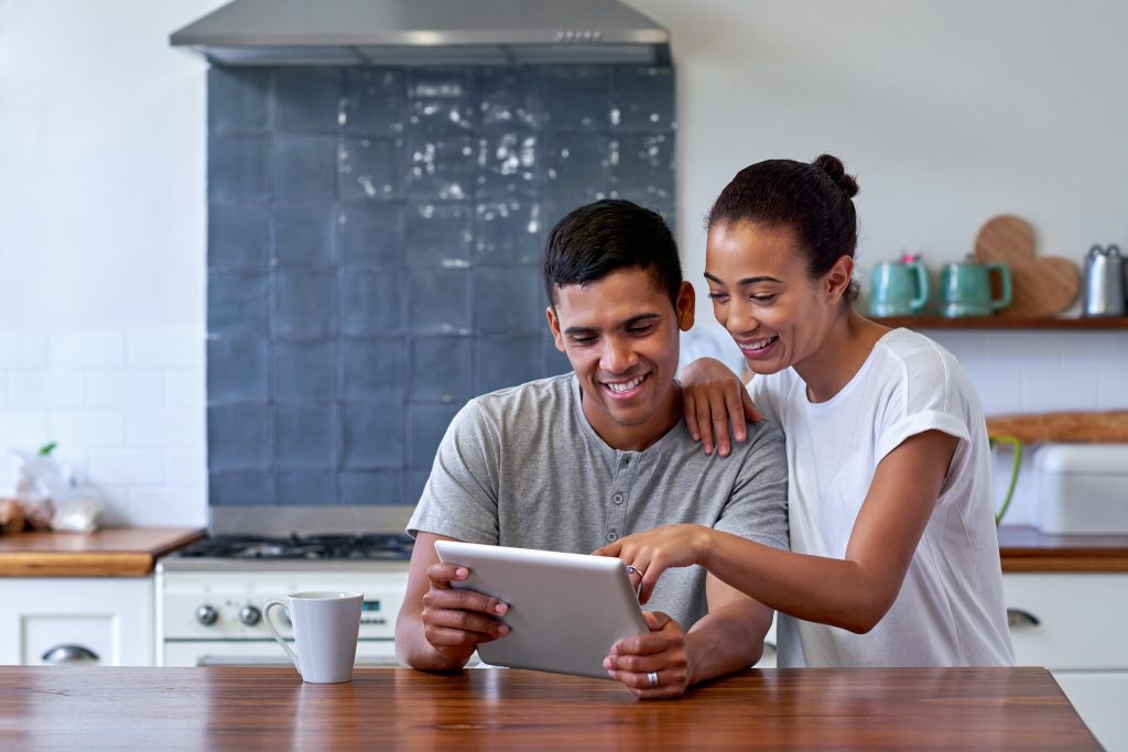 A couple in their kitchen, shopping for health plans on a tablet computer during the Anonymous shopping period at Your Health Idaho.