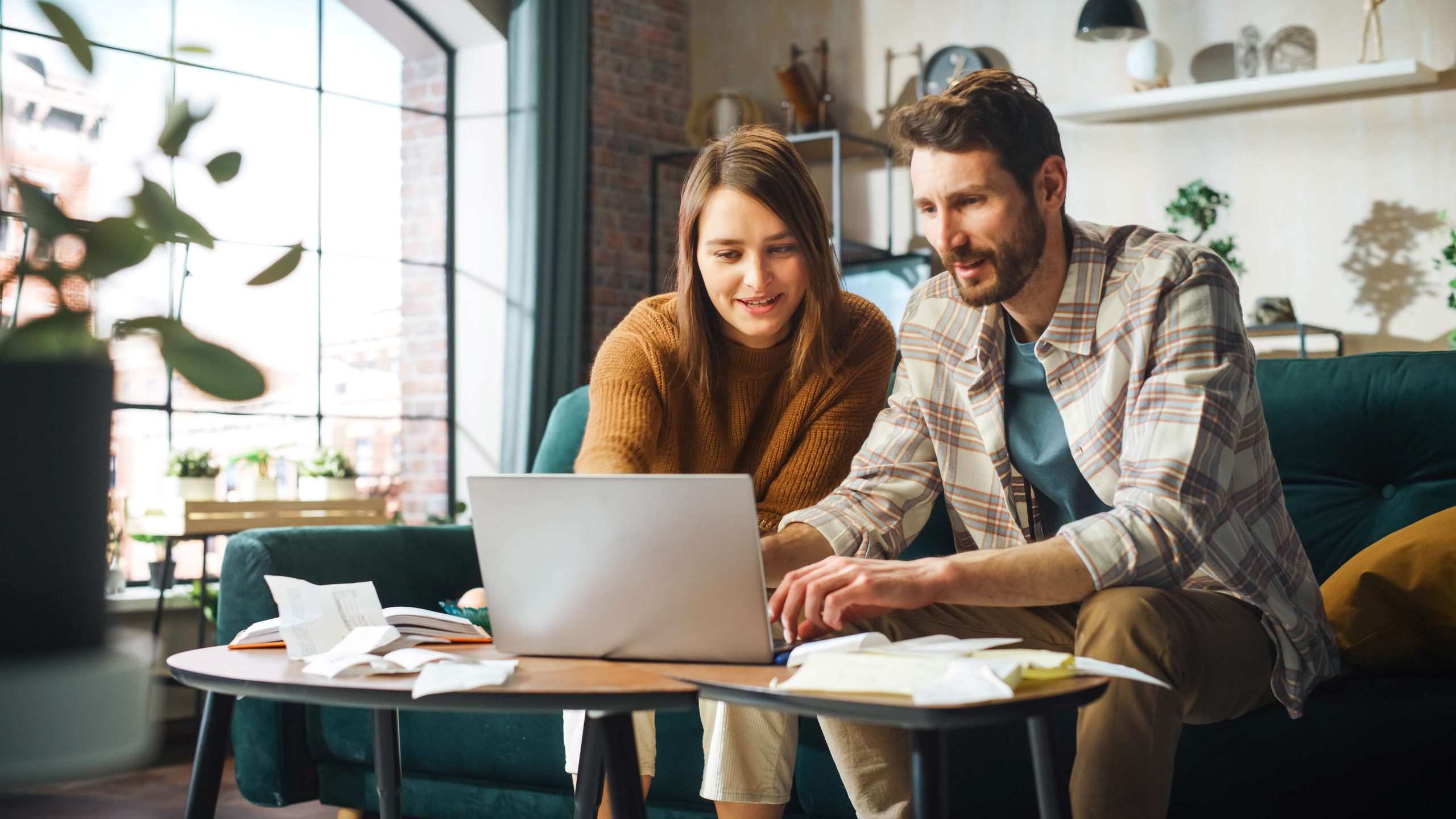 A couple sitting in their home and doing their income taxes on a computer.