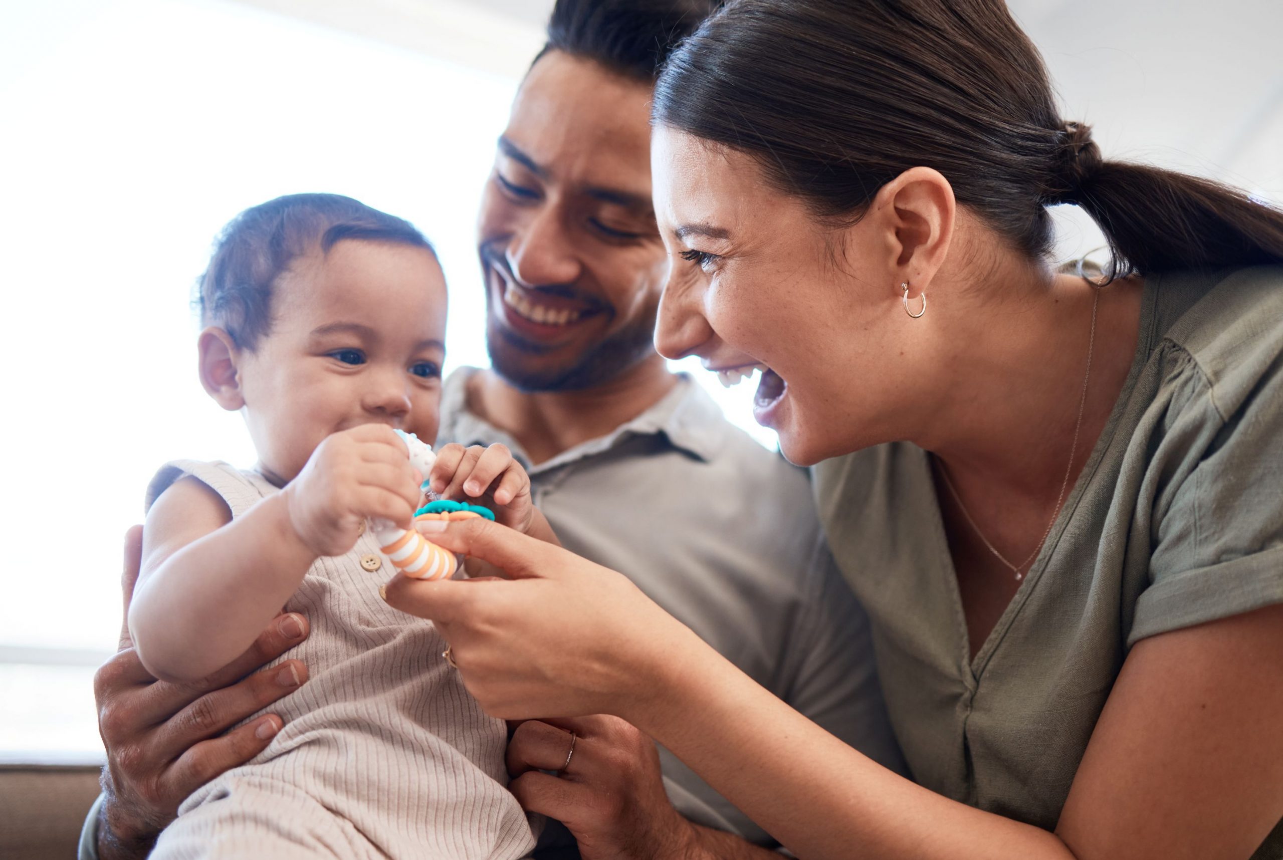 A young couple playing with their infant at home.