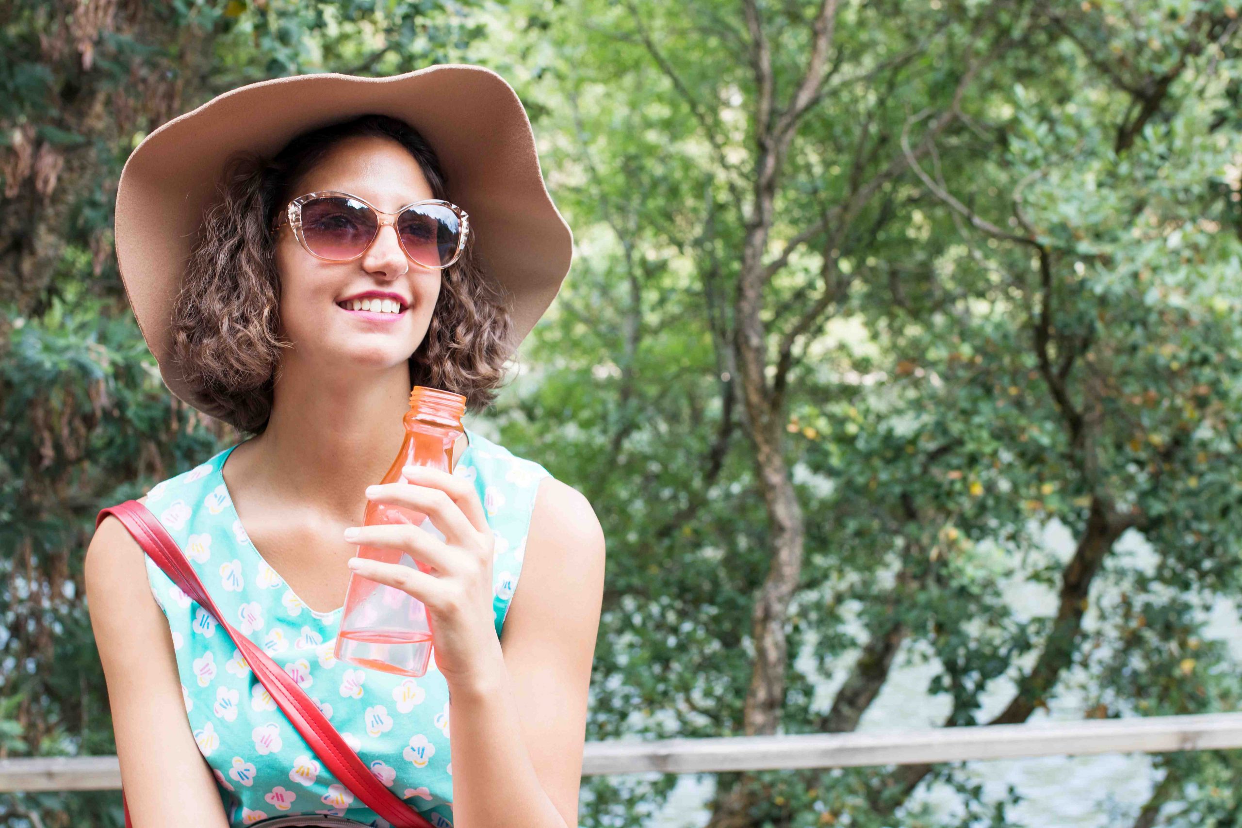 A young woman practicing summer safety by wearing sunscreen and a hat.